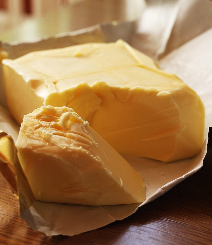 Fresh unwrapped butter on a table in a sunny kitchen