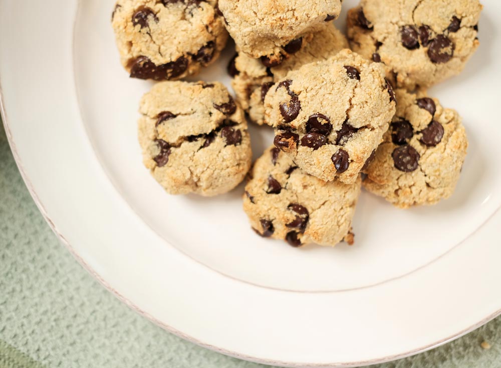 White glass plate with a bunch of chocolate chip cookies on them.